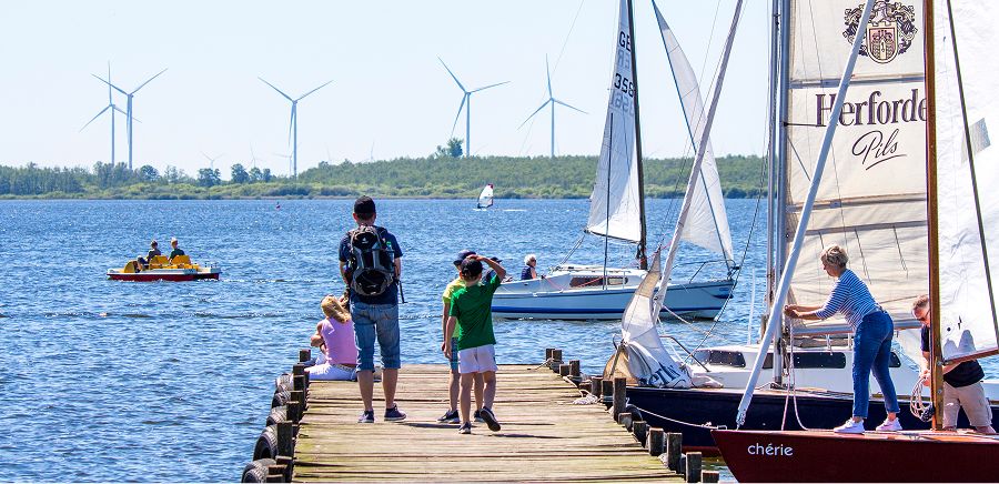 Dümmer See Niedersachsen - Familie auf Bootsanleger mit Segelbooten und Windrädern, Ausflugsziel Wassersport